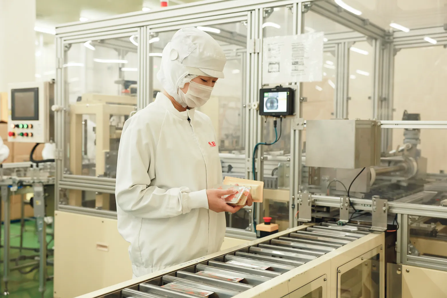 防塵衣・マスクを着用して製造ラインで製品を確認する従業員